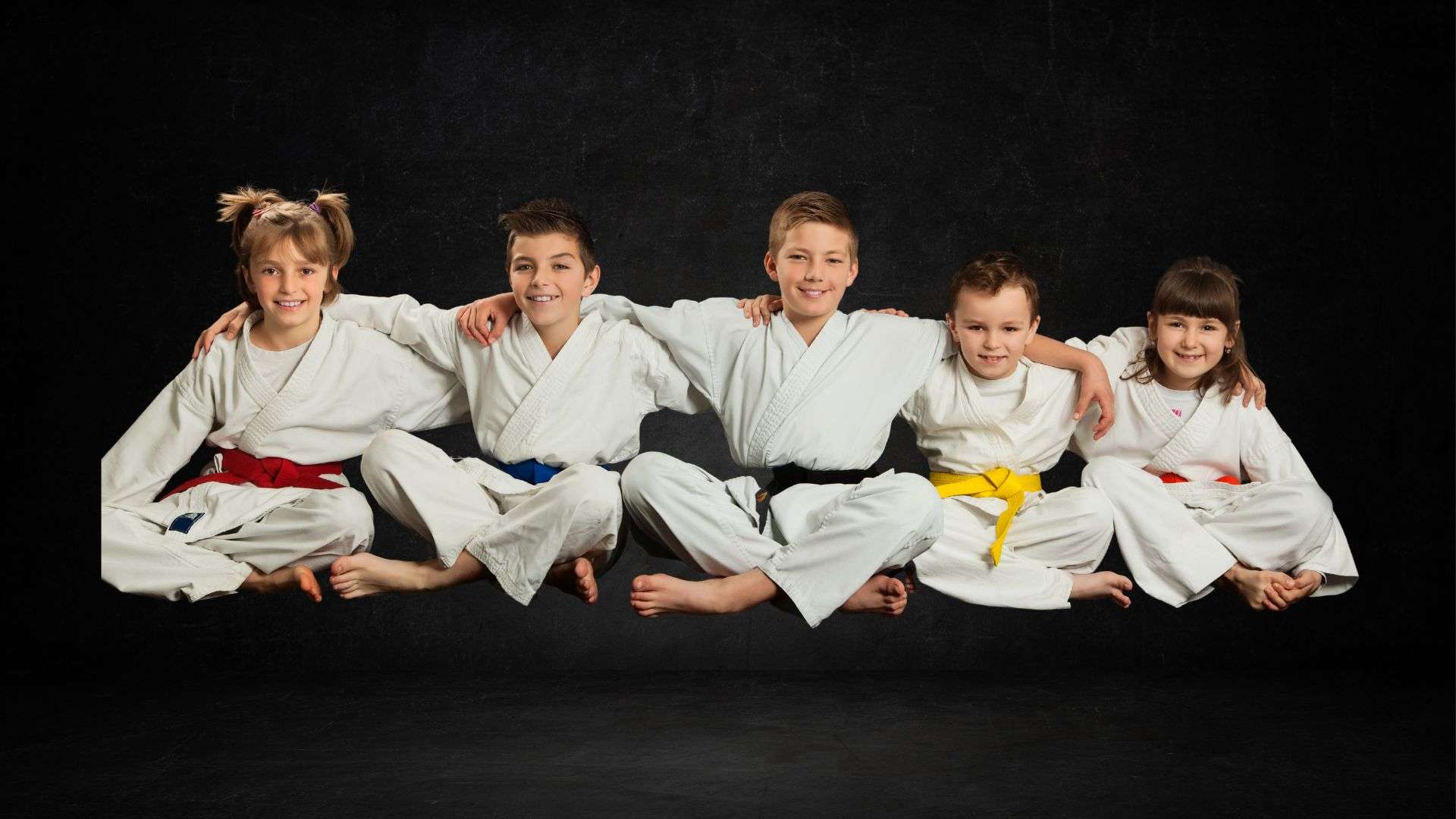 Karate kids sitting with hands over each others shoulder