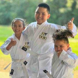 Kids smiling in Fitdojo martial arts outfits, showcasing the benefits of martial arts for kids' development.